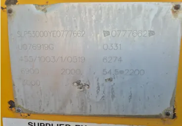Metalowa tabliczka znamionowa przytwierdzona do żółtego elementu. Na tabliczce znajduje się tekst: 'SLP53000YE0777662', '0777662', 'U076919G', '0331', '455/1003/1/0519', '6274', '6900', '2000', '54.5@2200' oraz 'T3000'. Powierzchnia tabliczki jest lekko zabrudzona i zmatowiała.