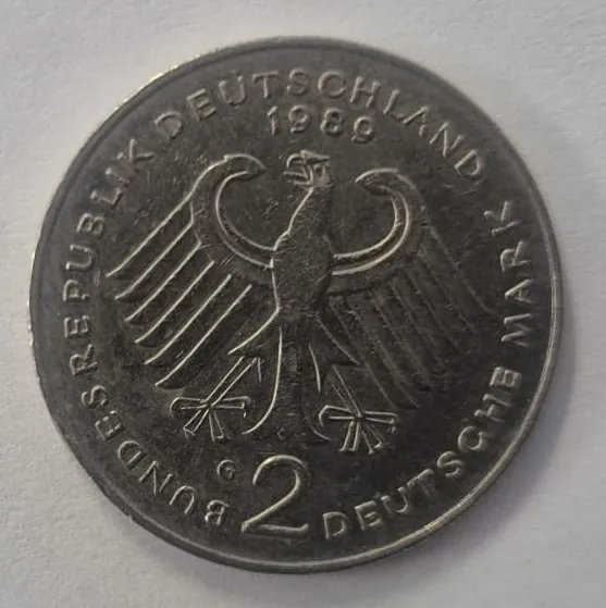 Srebrzysta moneta z wizerunkiem stylizowanego orła w centrum. Wzdłuż górnej i bocznej krawędzi widnieje napis „BUNDESREPUBLIK DEUTSCHLAND”, a po prawej stronie „DEUTSCHE MARK”. Na górze znajduje się data „1989”, a na dole liczba „2”.