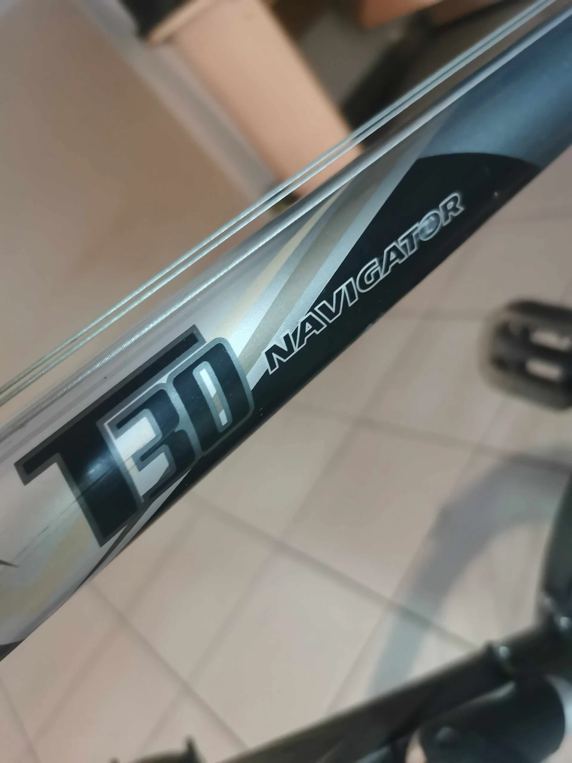 Zbliżenie na ramę roweru w kolorze srebrnym i czarnym z napisem 'T30 NAVIGATOR'. Tekst jest ułożony ukośnie.
