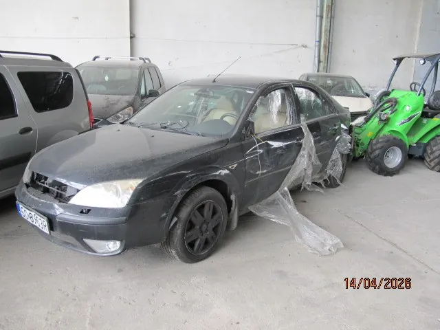 Czarny samochód osobowy typu sedan z zakrytymi plastikowymi foliami bokami, stojący na betonowej powierzchni. Widoczna tablica rejestracyjna CD-8705R. W tle: szary van, inny samochód oraz zielony traktor. Na ścianie betonowej i podłodze. W prawym dolnym rogu data 14/04/2026.