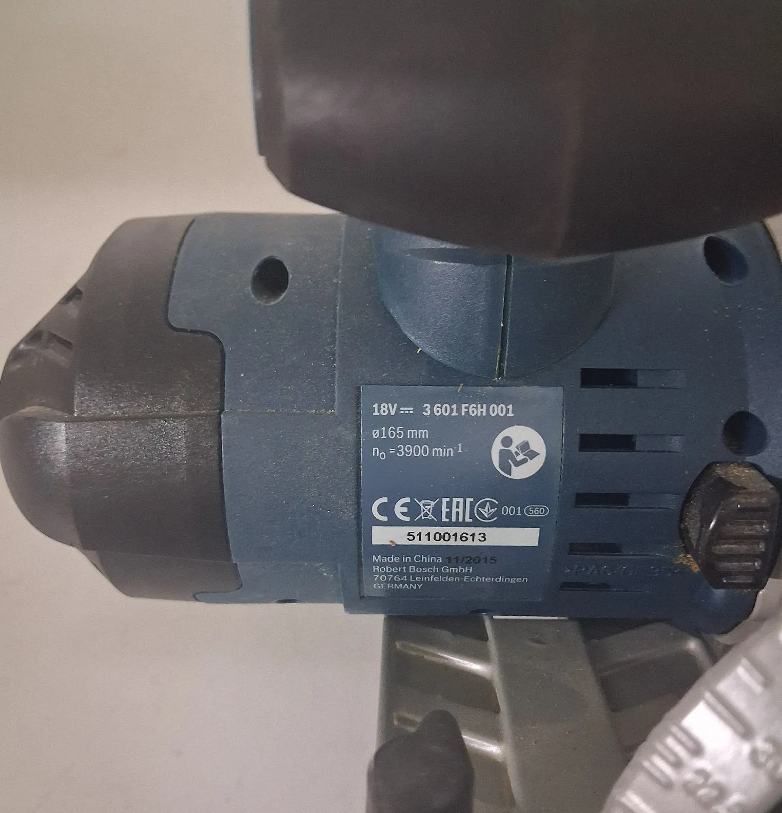 Zbliżenie na tabliczkę znamionową niebieskiego elektronarzędzia marki Bosch. Na srebrnej naklejce widnieją napisy: '18V ⎓ 3 601 F6H 001', 'ø165 mm', 'n₀ = 3900 min⁻¹', znaki certyfikacji CE i EAC, numer '001 560' oraz numer seryjny '511001613'. Poniżej znajduje się tekst: 'Made in China 11/2015 Robert Bosch GmbH 70764 Leinfelden-Echterdingen GERMANY'.