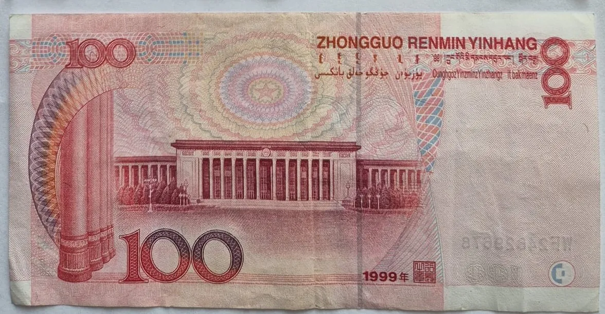 Chiński banknot o nominale 100 juanów w kolorze czerwonym i różowym. W centrum znajduje się ilustracja Bramy Niebiańskiego Spokoju w Pekinie. W prawym górnym rogu widnieje napis 'ZHONGGUO RENMIN YINHANG' oraz napisy w innych językach. Liczba '100' pojawia się w lewym górnym oraz w dolnej części banknotu. W prawym dolnym rogu widnieje data '1999年' oraz pieczęć.