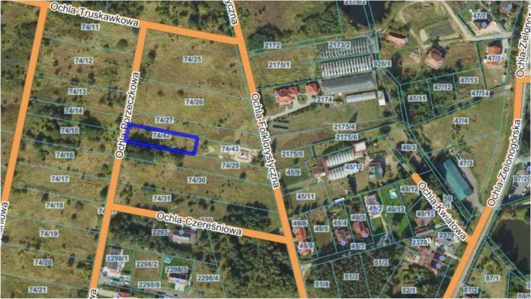 Mapa katastralna przedstawiająca działki z oznaczeniami numerów (np. 74/11, 74/12, 74/42), ulicami o nazwach Ochla-Truskawkowa, Ochla-Poręczkowa, Ochla-Folkowy Szcza, Ochla-Czeresniowa, Ochla-Kwiatowa, Ochla-Zielonogórska. Działka nr 74/42 zaznaczona niebieskim prostokątem. Widoczne budynki z czerwonymi dachami oraz struktury przemysłowe po prawej stronie. Linie graniczne działek oznaczone pomarańczowymi i niebieskimi liniami.
