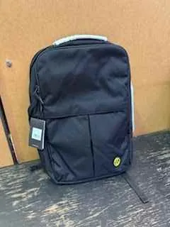 Czarna torba z przednią kieszenią i żółtym emblematem, z przywiązaną etykietą produktową, umieszczona na drewnianej powierzchni i brązowym tle.