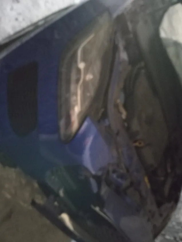 Niebieski samochód z otwartą maską, ukazujący silnik. Widoczna część przodu pojazdu, w tym reflektor i chłodnica. Samochód stoi na śnieżnej lub lodowej powierzchni. Obraz jest nieco rozmyty.