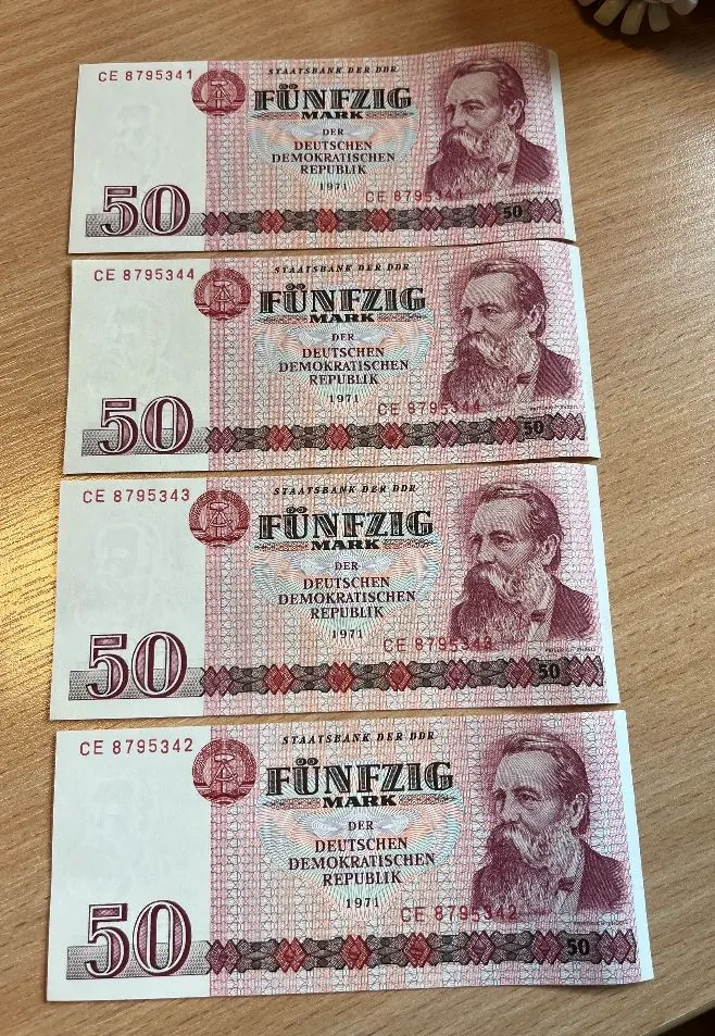 Cztery identyczne banknoty o nominale 50 marek z Niemieckiej Republiki Demokratycznej (NRD) ułożone pionowo jeden nad drugim. Banknoty są w kolorze różowo-beżowym i przedstawiają portret mężczyzny z brodą po prawej stronie. Na każdym banknocie widnieje napis 'STAATSBANK DER DDR', 'FÜNFZIG MARK DER DEUTSCHEN DEMOKRATISCHEN REPUBLIK' oraz rok '1971'. W lewym górnym rogu znajduje się numer seryjny, np. 'CE 8795341', a po lewej stronie duża liczba '50'.