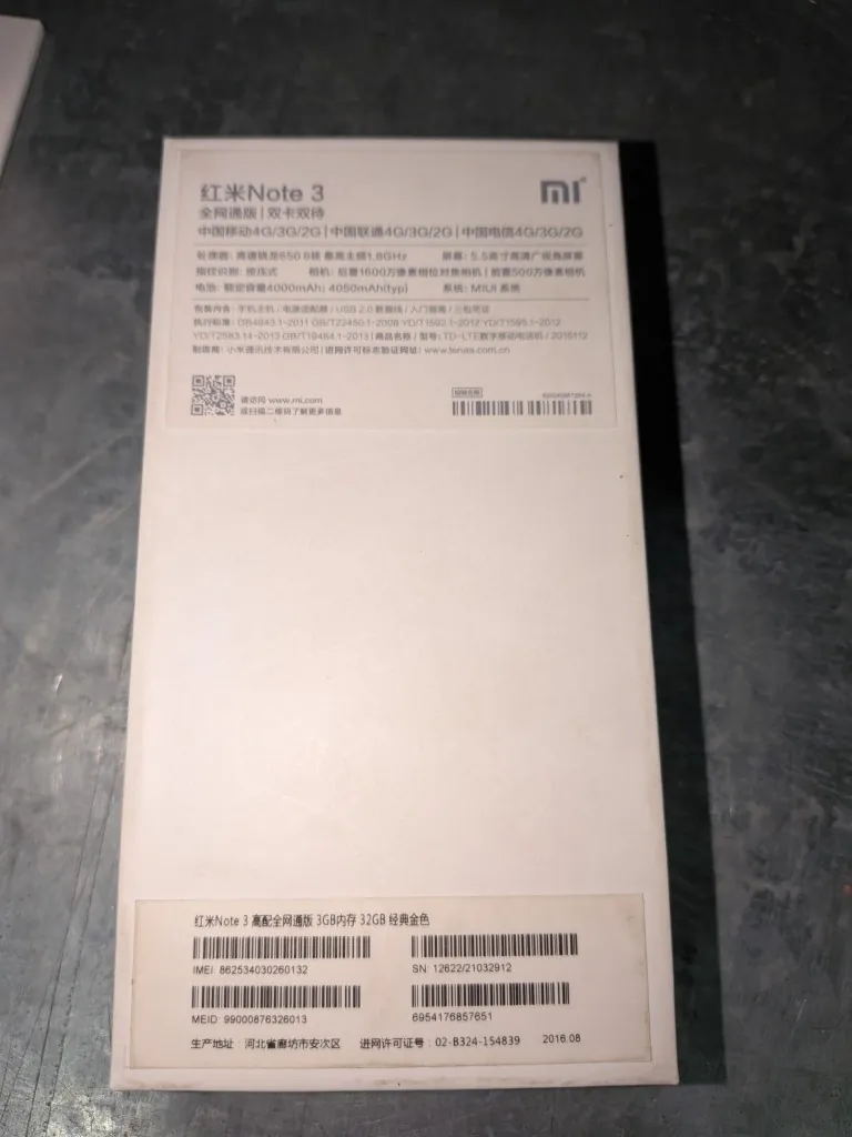 Zdjęcie białego, kartonowego opakowania telefonu Xiaomi Redmi Note 3. Na górnej części znajduje się logo Xiaomi oraz tekst w języku chińskim i angielskim: '红米Note 3', '全网通版 | 双卡双待'. Poniżej znajduje się szczegółowa specyfikacja techniczna urządzenia, w tym informacje o procesorze, ekranie, aparacie i baterii. W dolnej części opakowania widoczne są kody kreskowe oraz numery seryjne: IMEI: 862534030260132, SN: 12622/21032912 oraz MEID: 99000876326013. Na samym dole widnieje data 2016.08.