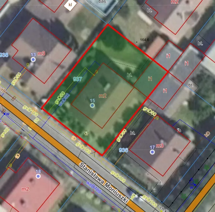 Widok z lotu ptaka na mapę geodezyjną z nałożonymi czerwonymi obrysami działek. Na mapie widoczne są budynki, tereny zielone oraz droga oznaczona nazwą 'Stanisława Moniuszki'. Na obrazie znajdują się liczne oznaczenia techniczne, takie jak 'm2', 'm3', 'gnD50', 'woD100' oraz numery działek, np. '937' i '936'.