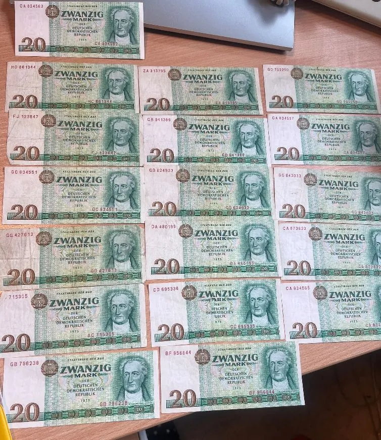 Kolekcja banknotów o nominale 20 marek z Niemieckiej Republiki Demokratycznej (ZWANZIG MARK). Banknoty są ułożone w rzędach na jasnej powierzchni. Na każdym z nich widnieje portret mężczyzny w profilu oraz napisy: 'DEUTSCHEN DEMOKRATISCHEN REPUBLIK' i rok '1975'.