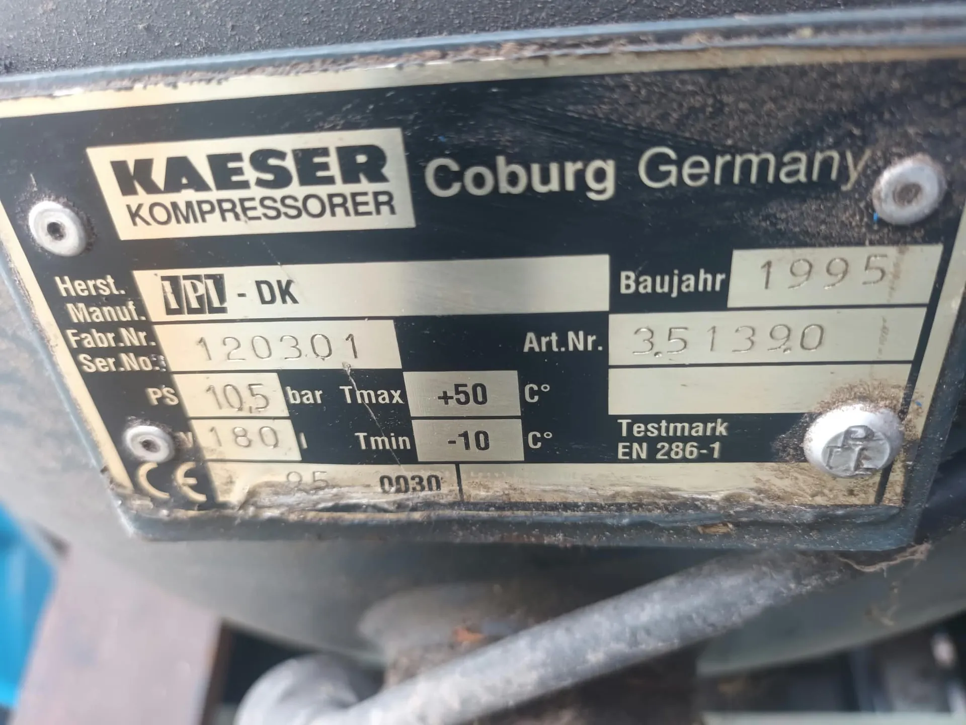 Metalowa tabliczka znamionowa urządzenia marki KAESER KOMPRESSORER z napisem Coburg Germany. Na tabliczce znajdują się następujące dane: Herst. Manuf. IPL - DK, Baujahr 1995, Fabr.Nr. Ser.No: 120301, Art.Nr. 351390, PS 10,5 bar, Tmax +50 C°, 180 l, Tmin -10 C°, Testmark EN 286-1. Widoczne są również oznaczenia CE oraz 0030.