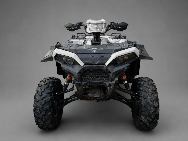 Widok z przodu na czarno-biały quad marki Polaris. Pojazd posiada szerokie, terenowe opony z głębokim bieżnikiem, białe elementy nadwozia na górze i czarne z przodu. Na przedniej masce widnieje napis POLARIS. Na górze znajduje się reflektor oraz kierownica z osłonami dłoni.