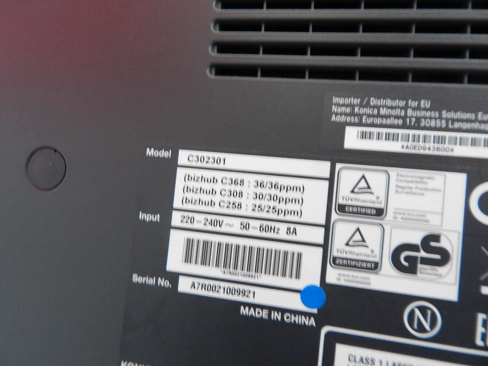 Zbliżenie na tabliczkę znamionową urządzenia elektronicznego. Widoczny jest model C302301 oraz lista kompatybilnych modeli: (bizhub C368 : 36/36ppm), (bizhub C308 : 30/30ppm), (bizhub C258 : 25/25ppm). Dane wejściowe (Input) to 220-240V, 50-60Hz, 8A. Numer seryjny (Serial No.) to A7R0021009921. Na tabliczce znajdują się kody kreskowe, certyfikaty TÜV Rheinland oraz znak GS. Na dole widnieje napis MADE IN CHINA.