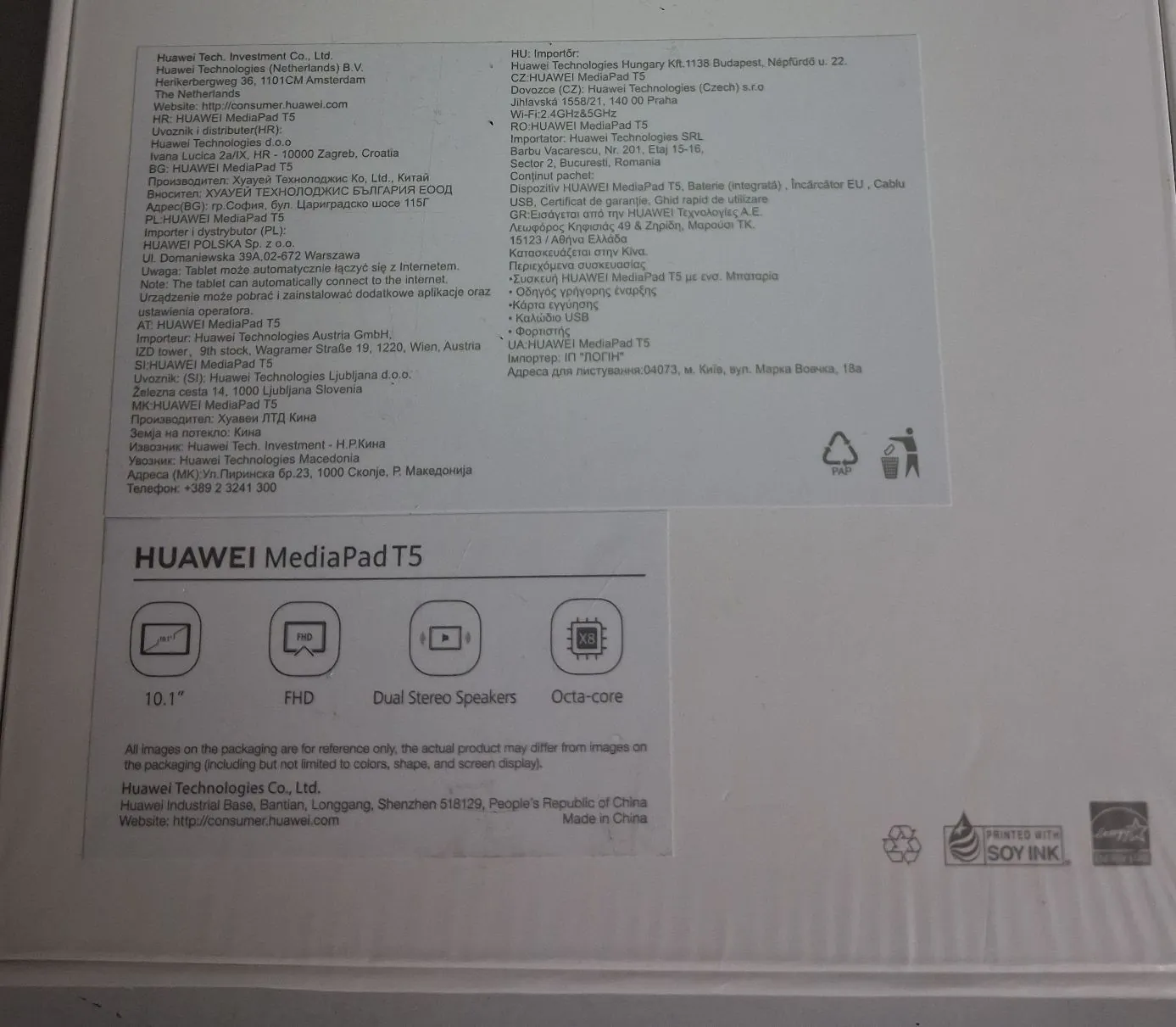 Zdjęcie białego opakowania produktu HUAWEI MediaPad T5. Na górnej części znajduje się szczegółowy tekst informacyjny w wielu językach, zawierający dane producenta i importerów z różnych krajów (m.in. Holandia, Czechy, Rumunia, Polska, Grecja, Bułgaria, Austria, Słowenia, Macedonia). Poniżej widnieje duży napis „HUAWEI MediaPad T5” oraz cztery ikony z opisami: ekran 10.1", rozdzielczość FHD, Dual Stereo Speakers oraz Octa-core. Na dole znajduje się informacja o producencie: Huawei Technologies Co., Ltd., adres w Chinach oraz strona internetowa. W prawym dolnym rogu widoczne jest logo „PRINTED WITH SOY INK”.