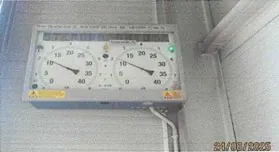 Przyrząd pomiarowy z dwoma okrągłymi wskaźnikami, z zakresem od 0 do 35. Wskaźniki pokazują wartości około 10 i 25. Na prawym górnym rogu przyrządu znajduje się zielona dioda. Widoczne są żółte etykiety ostrzegawcze. W prawym dolnym rogu obrazu data 21/05/2025. Przyrząd zamontowany na metalowej powierzchni.