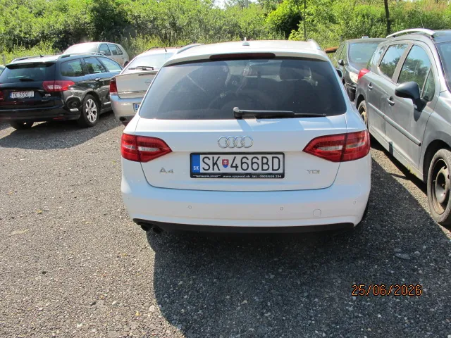 Tylny widok białego samochodu marki Audi A4 zaparkowanego na żwirowym placu. Samochód ma słowacką tablicę rejestracyjną o numerze SK 466BD. Po lewej stronie stoi czarny samochód z tablicą TK 555EJ, a po prawej szary samochód. W tle widoczna jest zielona roślinność. W prawym dolnym rogu zdjęcia znajduje się data 25/06/2026.