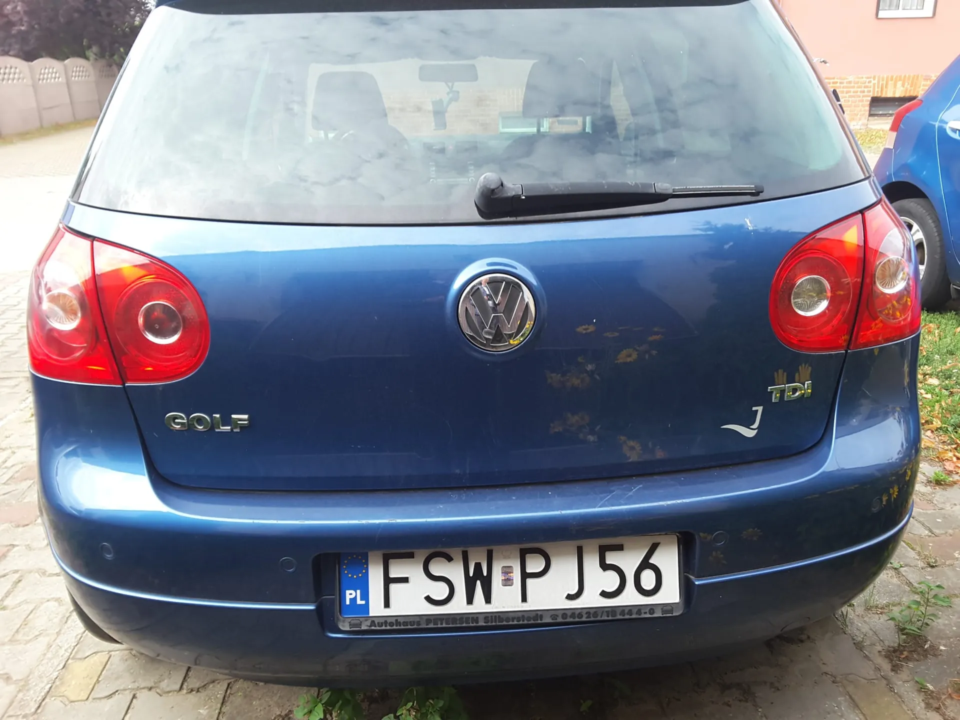 Tylny widok niebieskiego samochodu marki Volkswagen Golf. Na klapie bagażnika znajduje się logo Volkswagena, napis GOLF po lewej stronie oraz oznaczenie TDI po prawej. Samochód posiada polską tablicę rejestracyjną o numerze FSW PJ56.