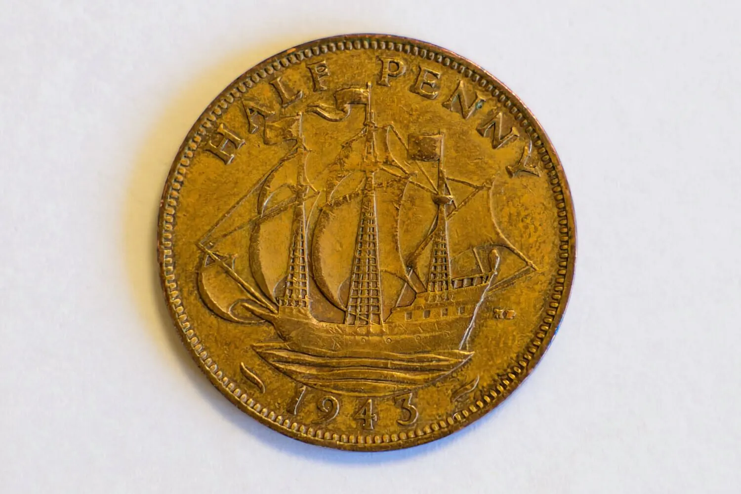 Zdjęcie brytyjskiej monety o nominale Half Penny z 1943 roku. Na awersie widnieje żaglowiec z trzema masztami. W górnej części monety znajduje się napis „HALF PENNY”, a na dole data „1943”. Moneta ma miedziany kolor i ząbkowany rant.