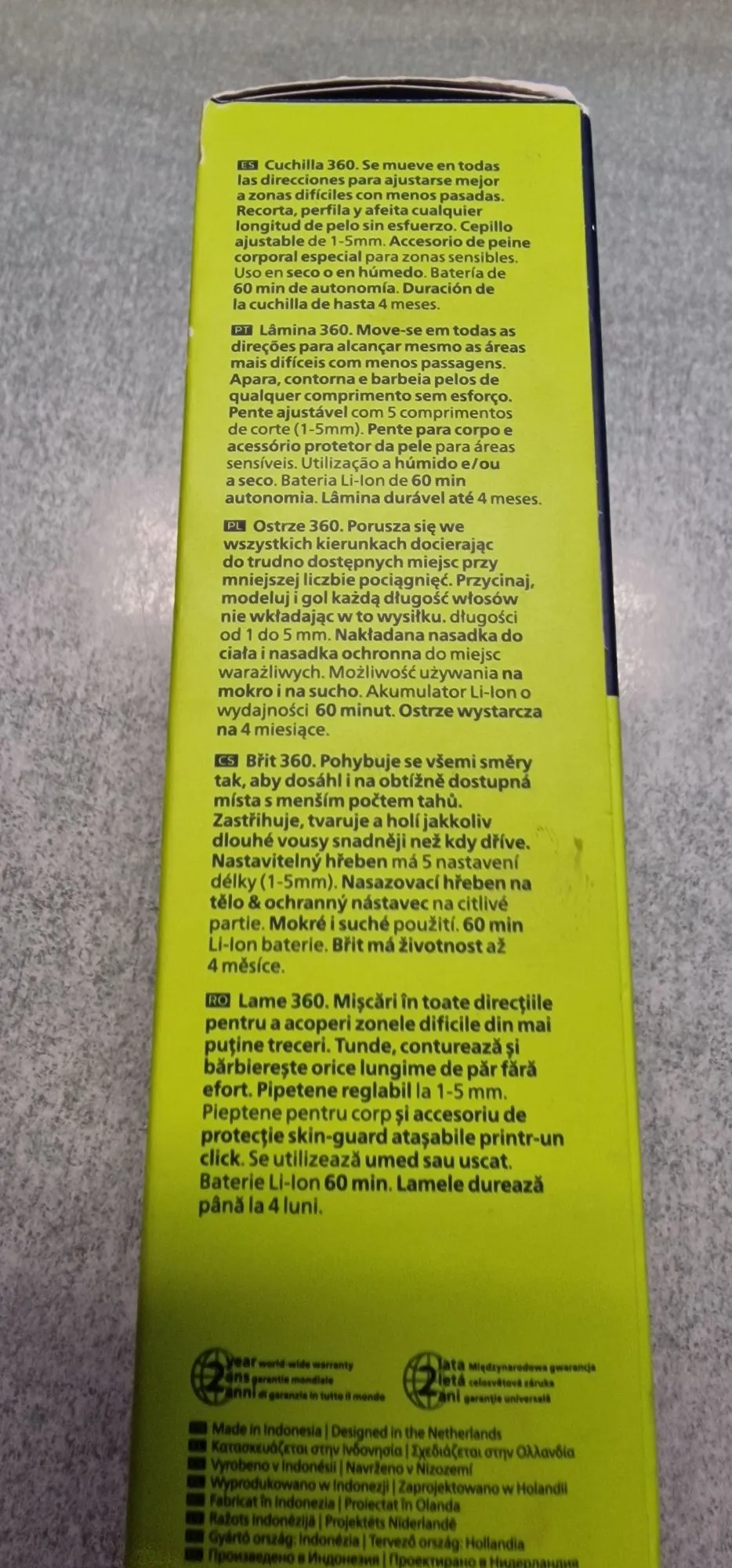 Zdjęcie fragmentu instrukcji obsługi w kilku językach. Tekst jest podzielony na sekcje oznaczone flagami krajów: Hiszpanii (ES), Portugalii (PT), Polski (PL), Czech (CS) i Rumunii (RO). Każda sekcja opisuje cechy produktu, prawdopodobnie trymera, wspominając o głowicy '360', regulowanej długości strzyżenia od 1 do 5 mm, nasadkach ochronnych oraz baterii Li-Ion o czasie pracy 60 minut. Na dole znajduje się sekcja dotycząca gwarancji międzynarodowej oraz informacja o produkcji w Indonezji i zaprojektowaniu w Holandii, zapisana w wielu językach.