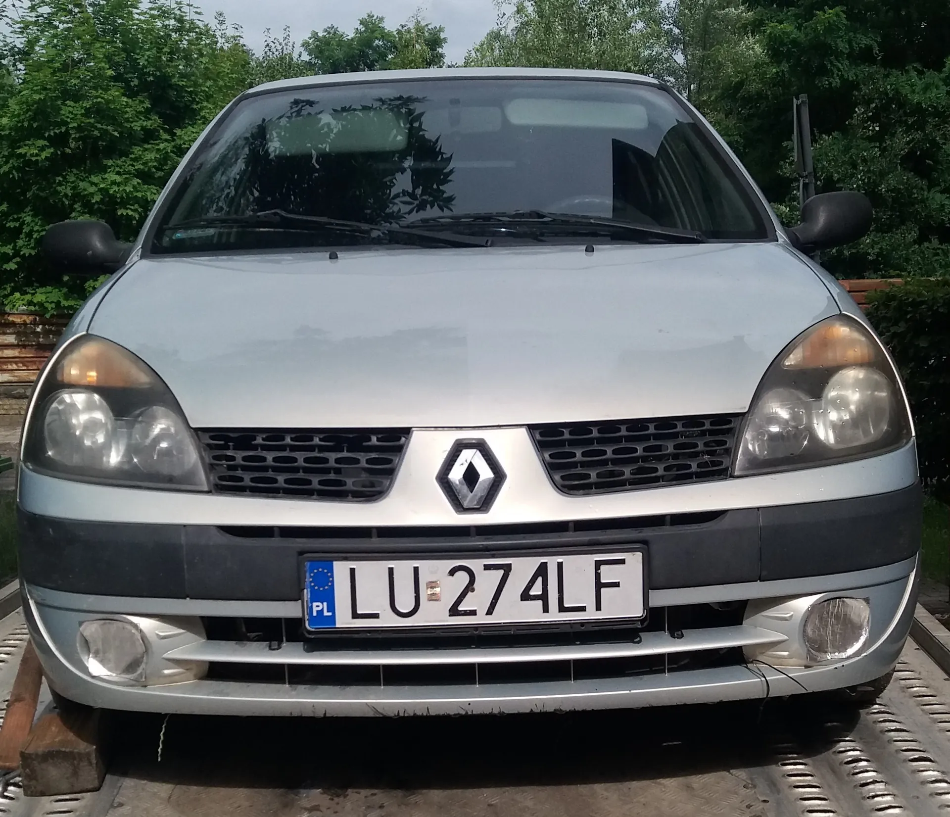 Srebrny samochód marki Renault widziany od przodu. Pojazd posiada polską tablicę rejestracyjną o numerze LU 274LF. Samochód stoi na platformie transportowej.