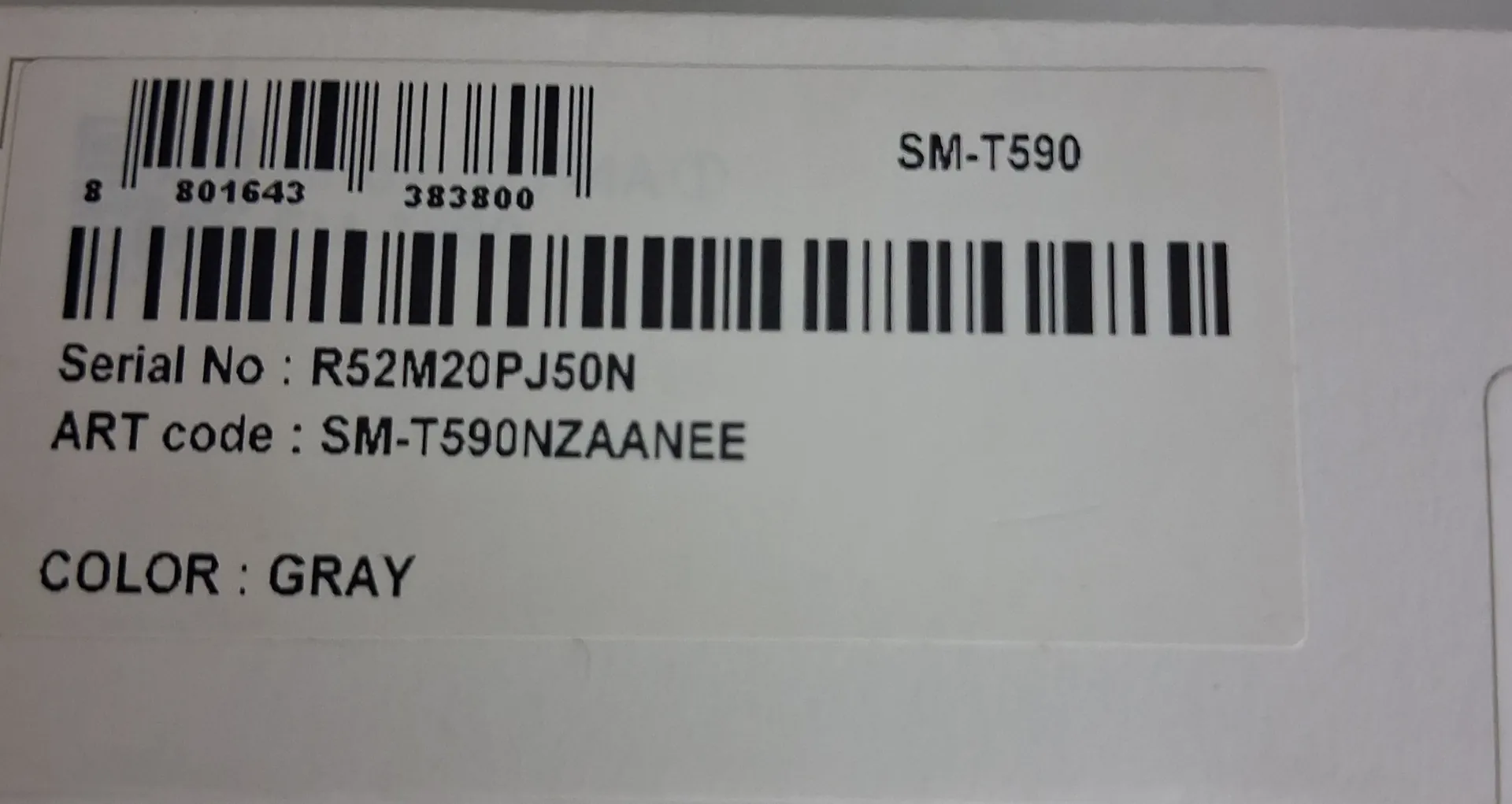 Biała etykieta z informacjami o produkcie. Na górze znajduje się kod kreskowy z numerami 8 801643 383800 oraz oznaczenie modelu SM-T590. Poniżej znajduje się drugi, dłuższy kod kreskowy. Pod kodami widnieją napisy: 'Serial No : R52M20PJ50N', 'ART code : SM-T590NZAANEE' oraz 'COLOR : GRAY'.