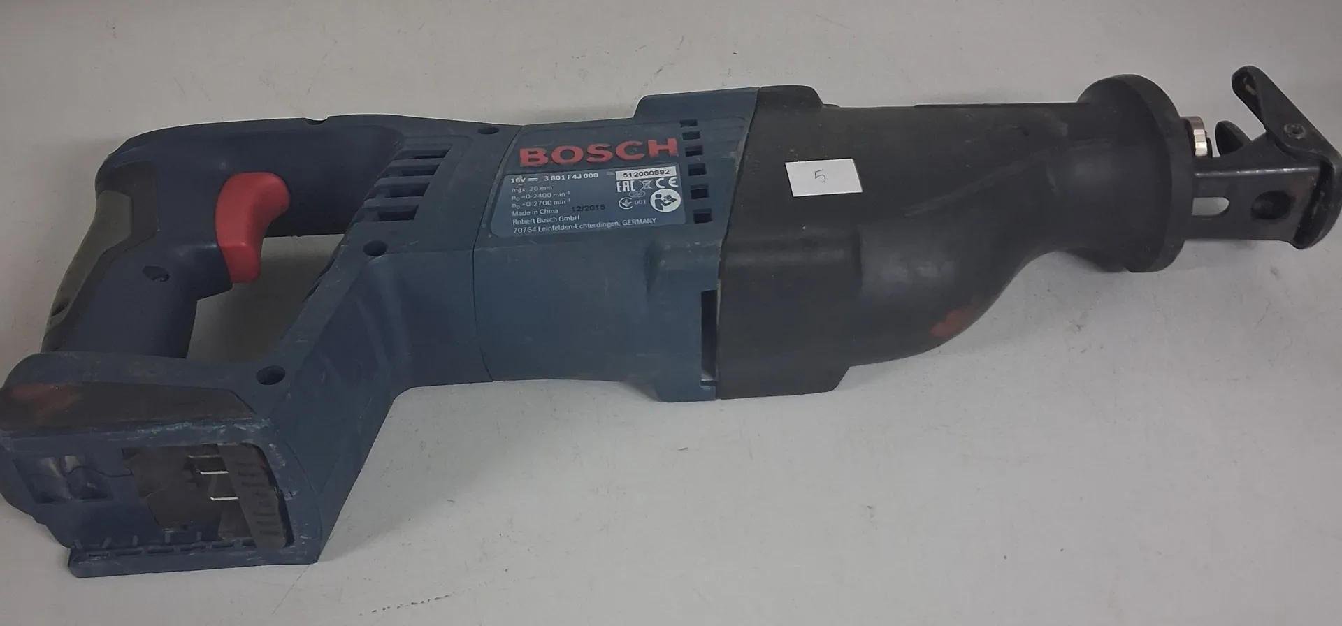 Niebiesko-czarna wiertarka akumulatorowa marki Bosch leżąca poziomo na białym tle. Na obudowie znajduje się srebrna tabliczka znamionowa z tekstem: 'BOSCH', '18V', '3 601 F4J 000', 'n0 0-2400 min-1', 'nmax 2400 min-1', 'Made in Malaysia 02/2015', 'Robert Bosch GmbH 70764 Leonfeld-Echterdingen, GERMANY' oraz oznaczeniami EAC i CE.