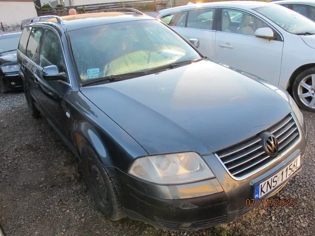 Czarny samochód osobowy typu kombi marki Volkswagen z tablicą rejestracyjną KNS 115A zaparkowany na żwirowym placu. Obok widoczny srebrny samochód osobowy. Na zdjęciu widoczny znaczek daty 07/11/2025 w prawym dolnym rogu. Tło zawiera fragmenty innych pojazdów i budynków.