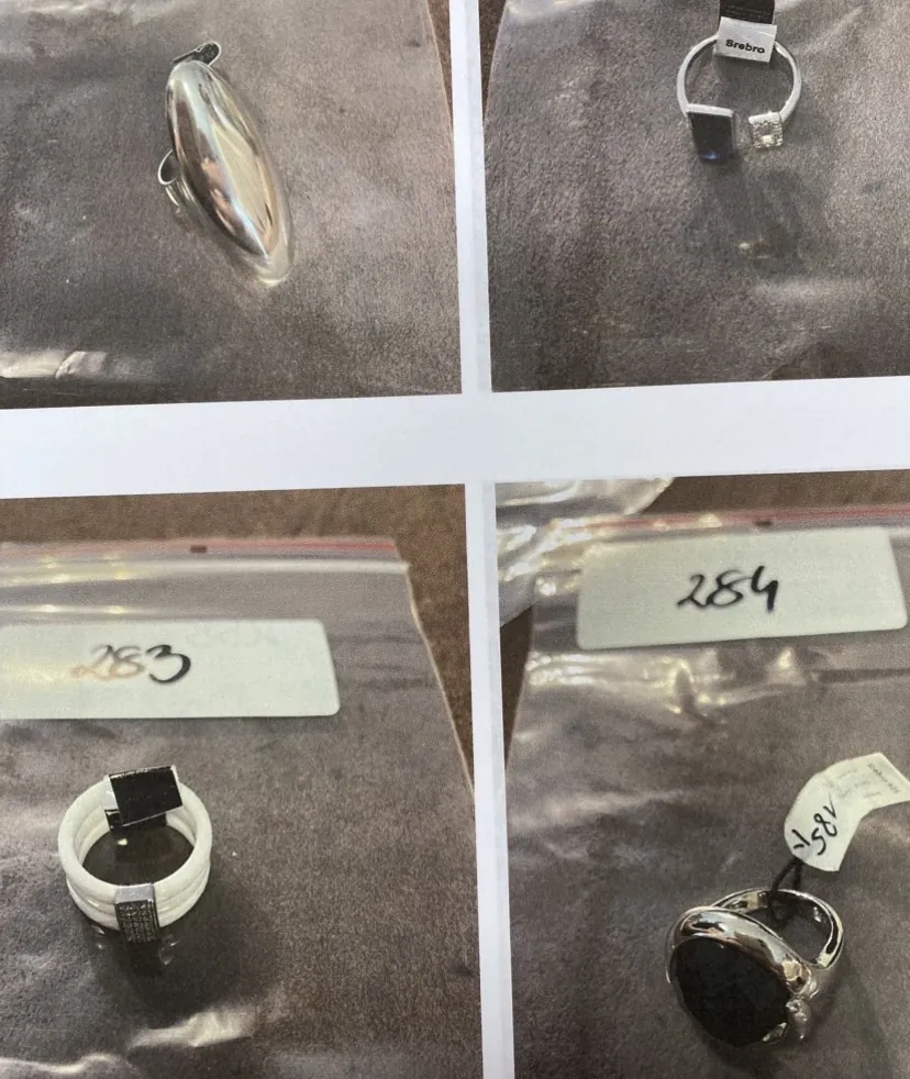 Kolaż czterech zdjęć przedstawiających biżuterię w plastikowych woreczkach. W lewym górnym rogu znajduje się srebrny, owalny wisiorek. W prawym górnym rogu srebrny pierścionek z ciemnym kamieniem i małą etykietą z napisem 'Srebro'. W lewym dolnym rogu biały pierścionek z ciemnym, kwadratowym elementem, nad którym widnieje etykieta z numerem '283'. W prawym dolnym rogu srebrny pierścionek z dużym, czarnym, owalnym kamieniem, z etykietą z numerem '284' powyżej oraz mniejszą etykietą z numerem '185' obok.