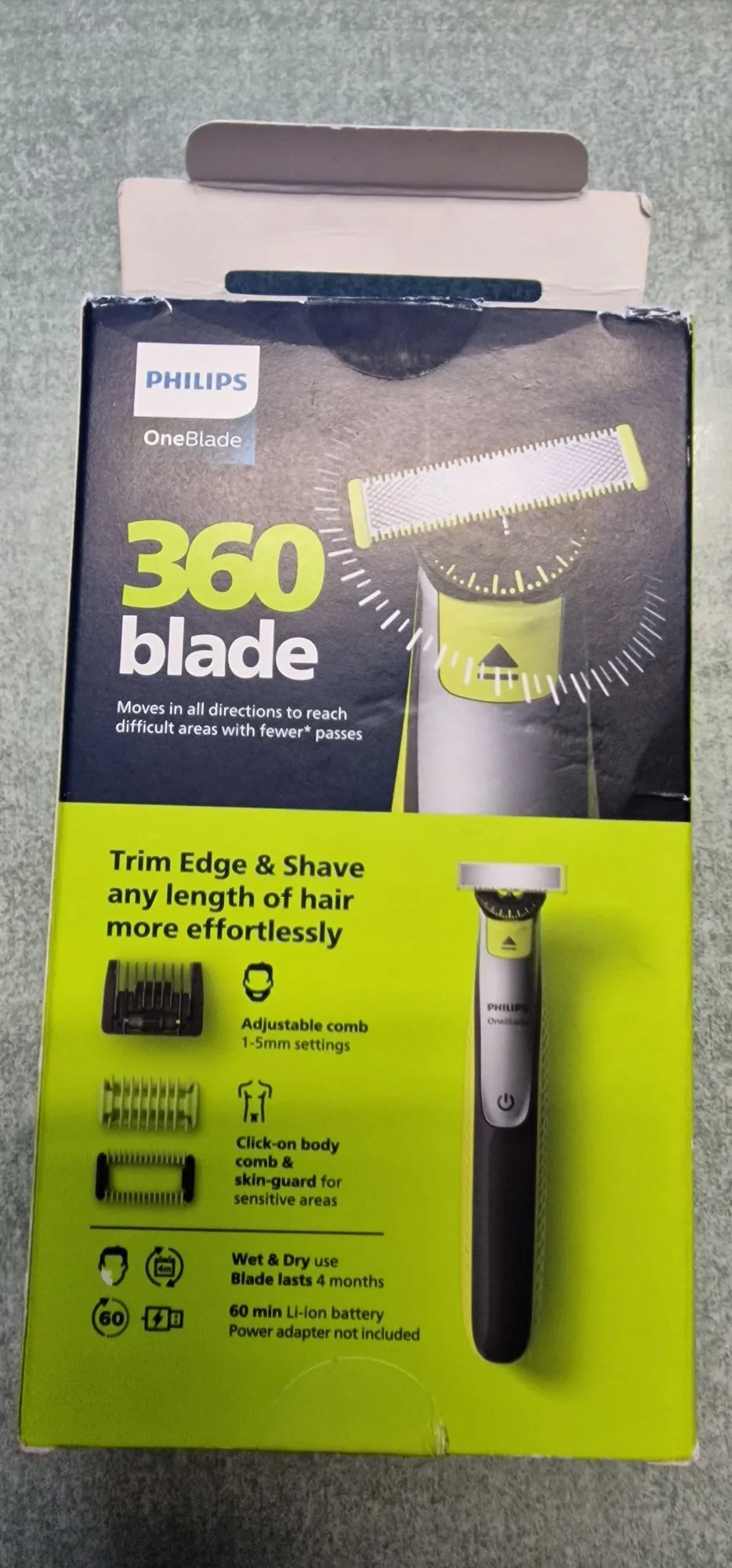 Opakowanie trymera Philips OneBlade 360 blade. Górna część pudełka jest ciemnoniebieska i przedstawia zbliżenie na głowicę urządzenia z napisem '360 blade' oraz tekstem 'Moves in all directions to reach difficult areas with fewer* passes'. Dolna część pudełka jest jasnozielona i zawiera zdjęcie całego urządzenia w kolorze czarnym z żółtymi akcentami oraz ikony i opisy funkcji: 'Trim Edge & Shave any length of hair more effortlessly', 'Adjustable comb 1-5mm settings', 'Click-on body comb & skin-guard for sensitive areas', 'Wet & Dry use', 'Blade lasts 4 months' oraz '60 min Li-ion battery Power adapter not included'.