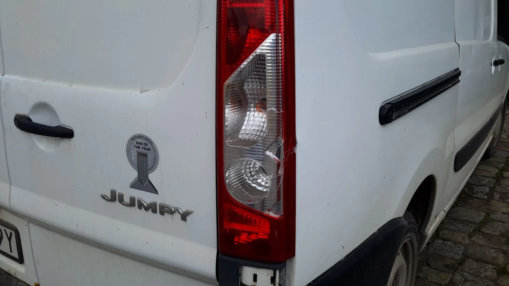 Zbliżenie na tył białego vana. Widoczna jest pionowa lampa tylna w kolorach czerwonym i białym, a obok niej napis 'JUMPY' oraz okrągła naklejka z tekstem 'INTERNATIONAL VAN OF THE YEAR 2008'. Po prawej stronie widoczny jest fragment boku pojazdu z czarną listwą ochronną.