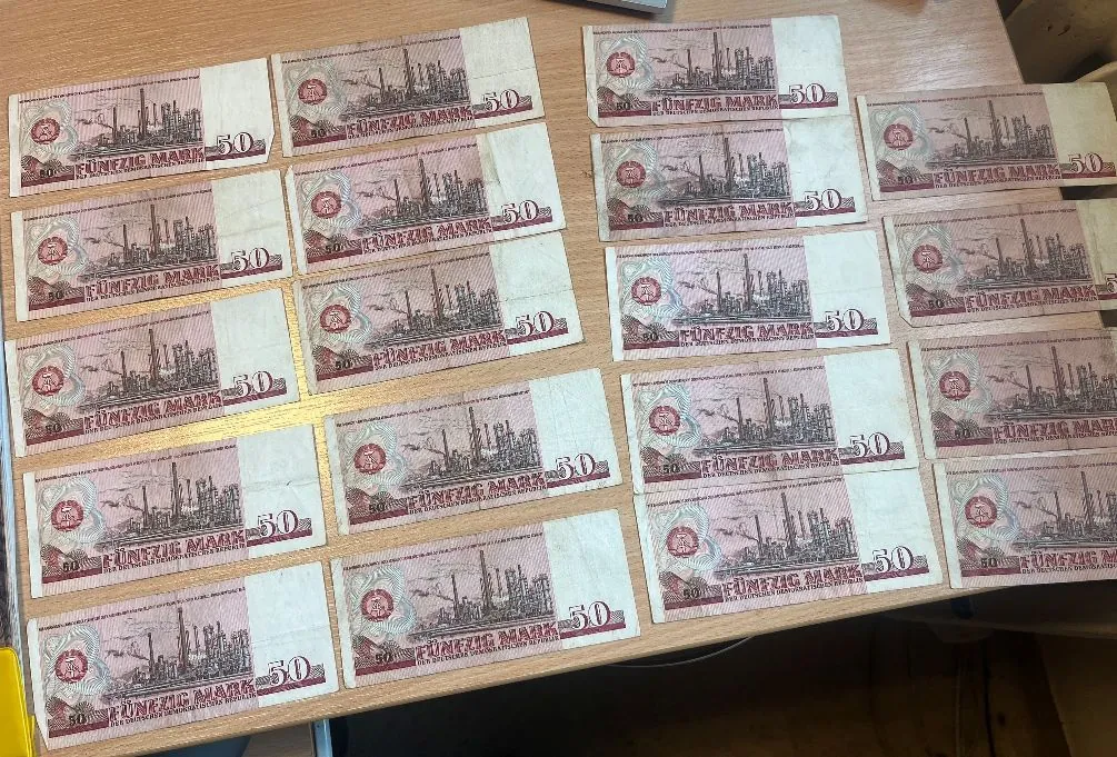 Kolekcja banknotów o nominale 50 Mark (Fünfzig Mark) ułożonych w rzędach na jasnym blacie. Banknoty mają czerwono-brązową kolorystykę i przedstawiają industrialny krajobraz z kominami fabrycznymi.