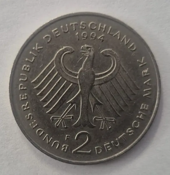 Zdjęcie niemieckiej monety o nominale 2 Deutsche Mark z 1994 roku. W centrum znajduje się wizerunek stylizowanego orła. Wzdłuż górnego i bocznego brzegu widnieje napis „BUNDESREPUBLIK DEUTSCHLAND”, a na dole „2 DEUTSCHE MARK”. Na górze, nad orłem, widnieje data „1994”.