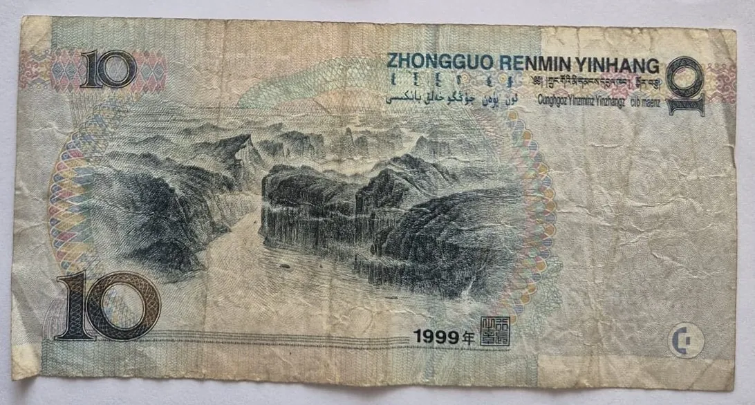 Chiński banknot o nominale 10 juanów z 1999 roku. Na banknocie widnieje grawerowany krajobraz z wysokimi, skalistymi górami i rzeką przepływającą przez kanion. W górnej części znajduje się napis 'ZHONGGUO RENMIN YINHANG' oraz teksty w innych językach i pismach. W rogach widoczna jest cyfra '10', a na dole data '1999年' wraz z pieczęcią.
