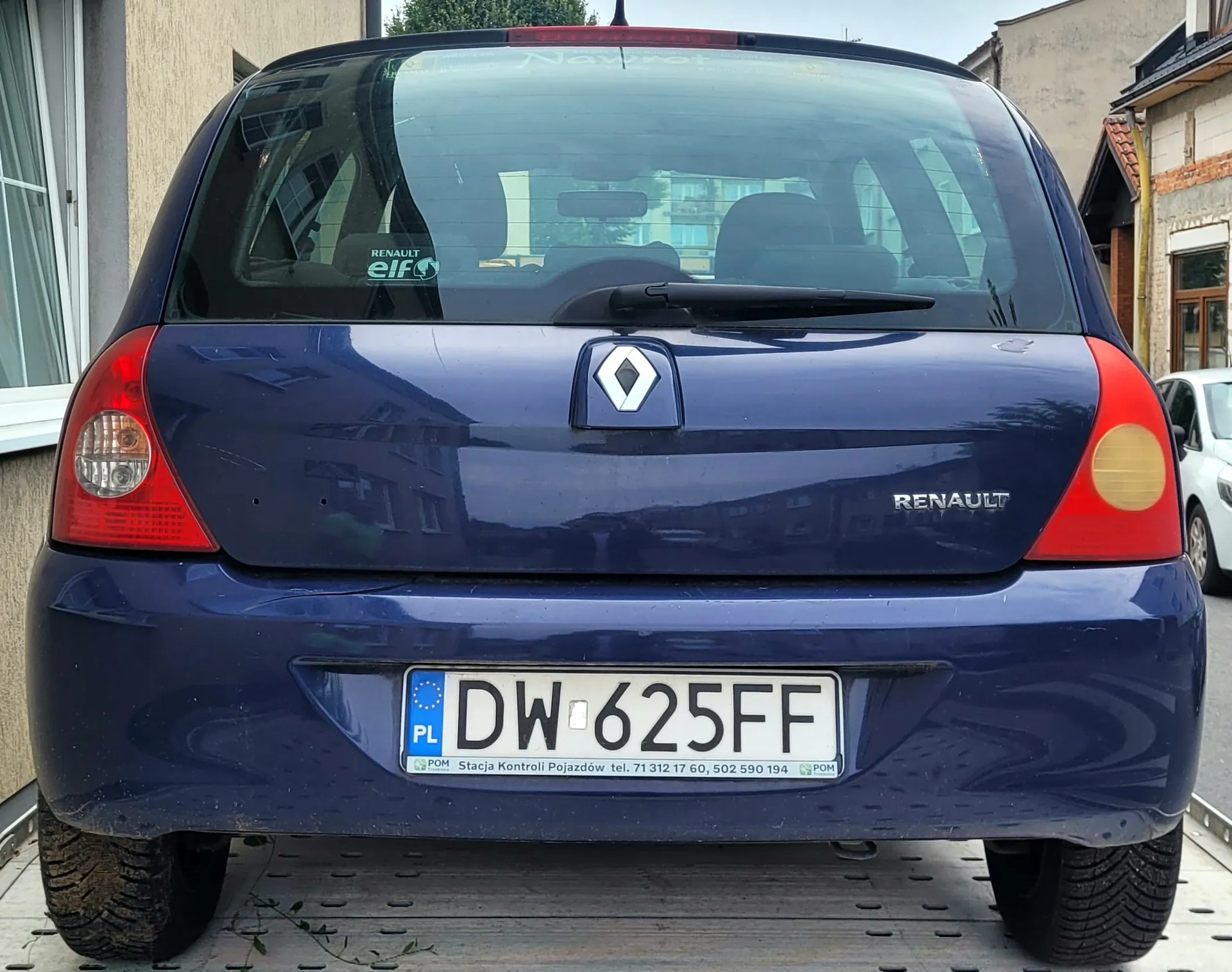 Tylny widok ciemnoniebieskiego samochodu marki Renault. Na klapie bagażnika znajduje się logo Renault oraz napis 'RENAULT'. Samochód posiada polską tablicę rejestracyjną o numerze 'DW 625FF'. Poniżej numeru rejestracyjnego widnieje napis: 'POM Stacja Kontroli Pojazdów tel. 71 312 17 60, 502 590 194 POM'. W tylnej szybie widoczna jest naklejka 'RENAULT elf'.