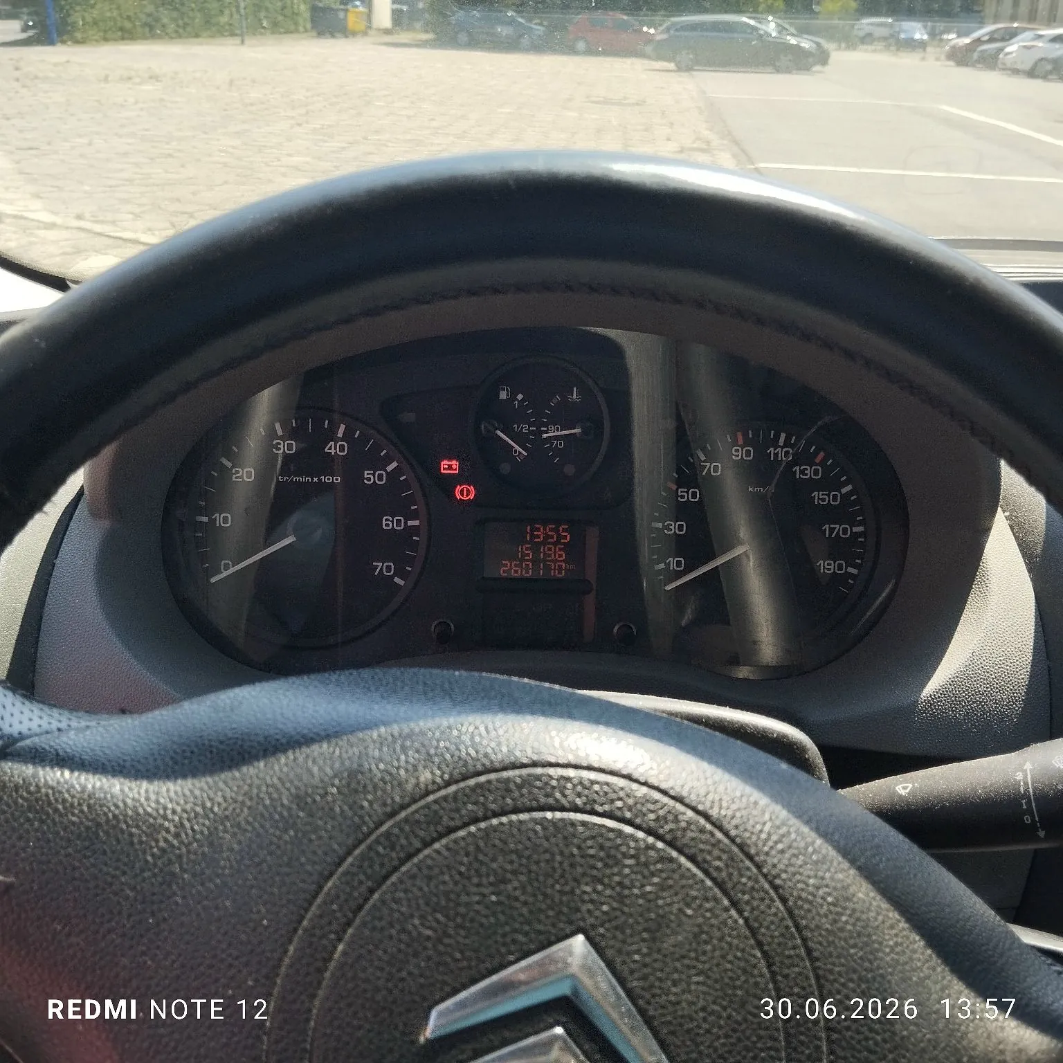 Widok z perspektywy kierowcy na deskę rozdzielczą samochodu marki Citroën. W centrum znajduje się zestaw wskaźników: obrotomierz po lewej, prędkościomierz po prawej oraz wskaźnik temperatury cieczy chłodzącej na górze. W centralnym wyświetlaczu cyfrowym widnieją czerwone napisy: godzina 13:55, przebieg 15196 oraz wartość 260170. Na dole obrazu widoczne jest logo Citroëna na kierownicy oraz znaki wodne: 'REDMI NOTE 12' i data '30.06.2026 13:57'.