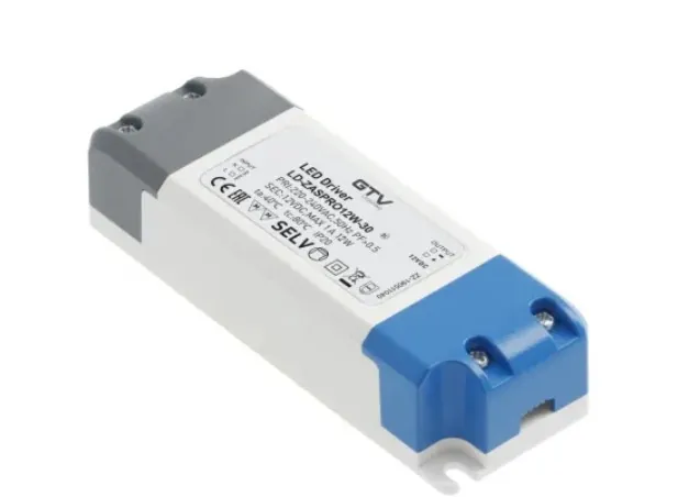 Biały, podłużny zasilacz LED Driver marki GTV, model LD-ZASPRO12W-30. Urządzenie ma szare zakończenie z jednej strony i niebieskie z drugiej. Na białej obudowie znajduje się czarny tekst z parametrami technicznymi: 'LED Driver GTV LD-ZASPRO12W-30 PRI: 200-240VAC, 50Hz, PF=0,5 SEC: 12VDC MAX 1A, 12W ta: -40°C tc: 80°C IP20' oraz oznaczenia CE, EAC, SELV i inne symbole certyfikacji.
