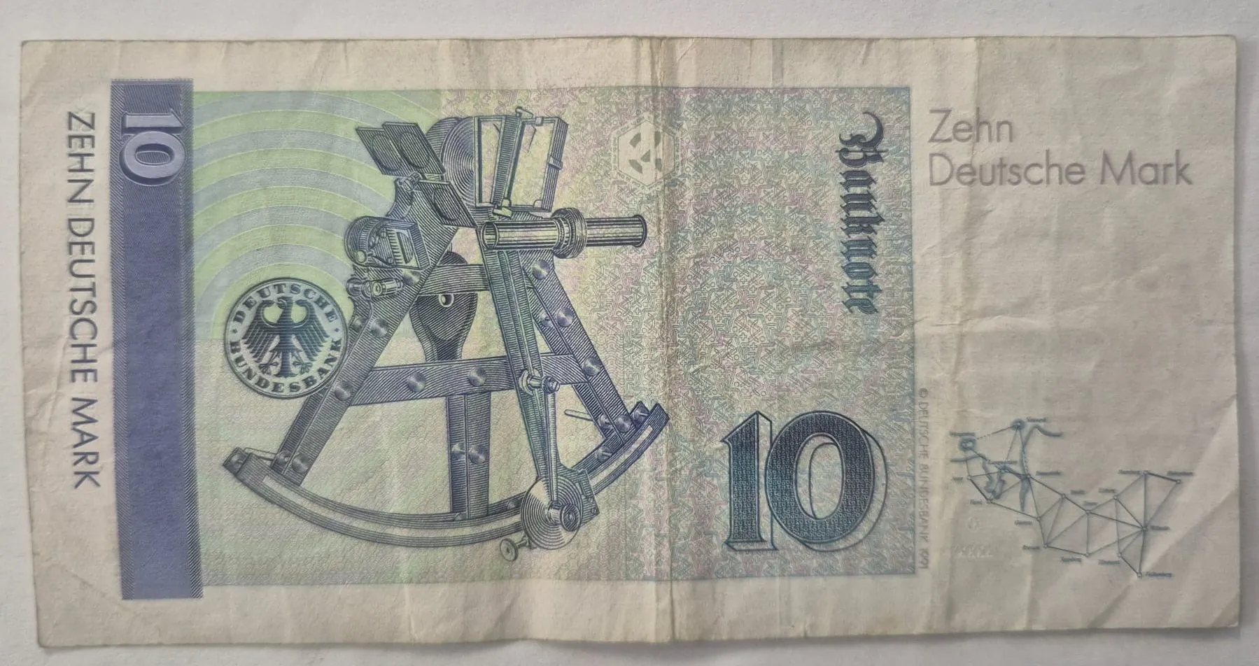 Niemiecki banknot o nominale 10 marek niemieckich (Zehn Deutsche Mark). Na banknocie widnieje duża cyfra 10 w lewym górnym i prawym dolnym rogu oraz rysunek instrumentu astronomicznego. Po lewej stronie znajduje się pionowy napis 'ZEHN DEUTSCHE MARK', a po prawej 'Zehn Deutsche Mark' oraz pionowy napis 'Banknote'. Widoczne jest logo Deutsche Bundesbank.