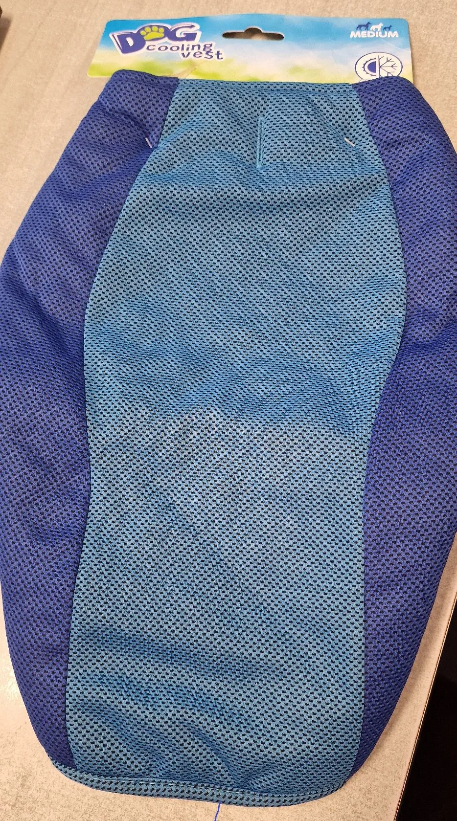 Niebieska chłodząca kamizelka dla psa wykonana z oddychającej siateczki. Produkt znajduje się na opakowaniu z napisem 'DOG cooling vest' oraz oznaczeniem rozmiaru 'MEDIUM'.