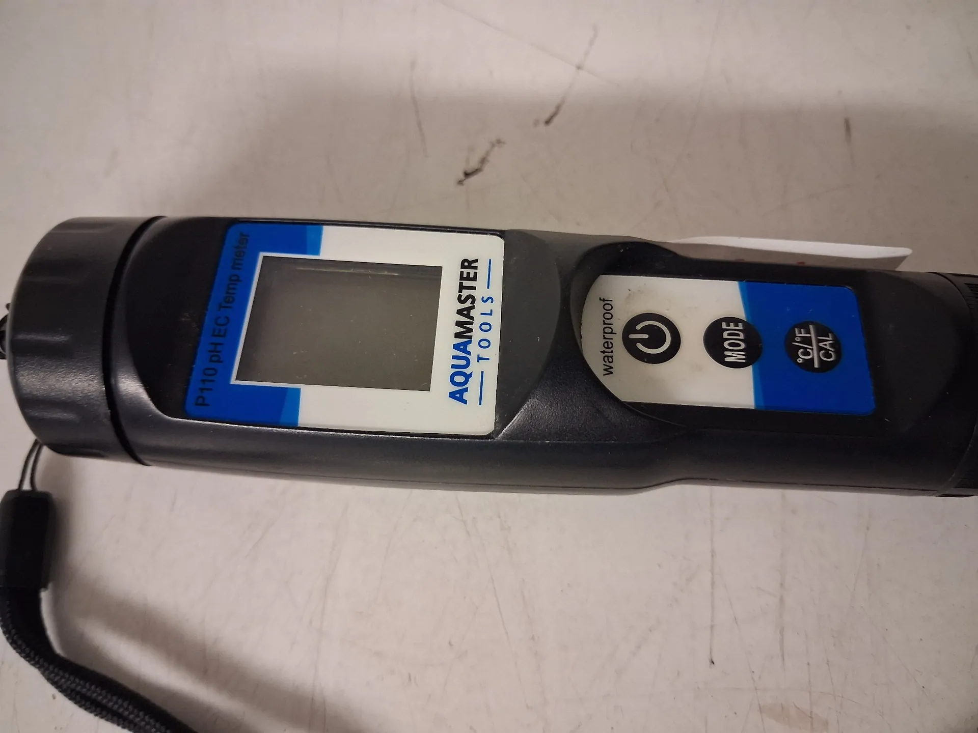Czarny, przenośny miernik parametrów wody marki AQUAMASTER TOOLS. Urządzenie posiada ekran LCD oraz przyciski: zasilania, MODE oraz °C/°F CAL. Na obudowie widnieje napis 'P110 pH EC Temp meter' oraz oznaczenie 'waterproof'.