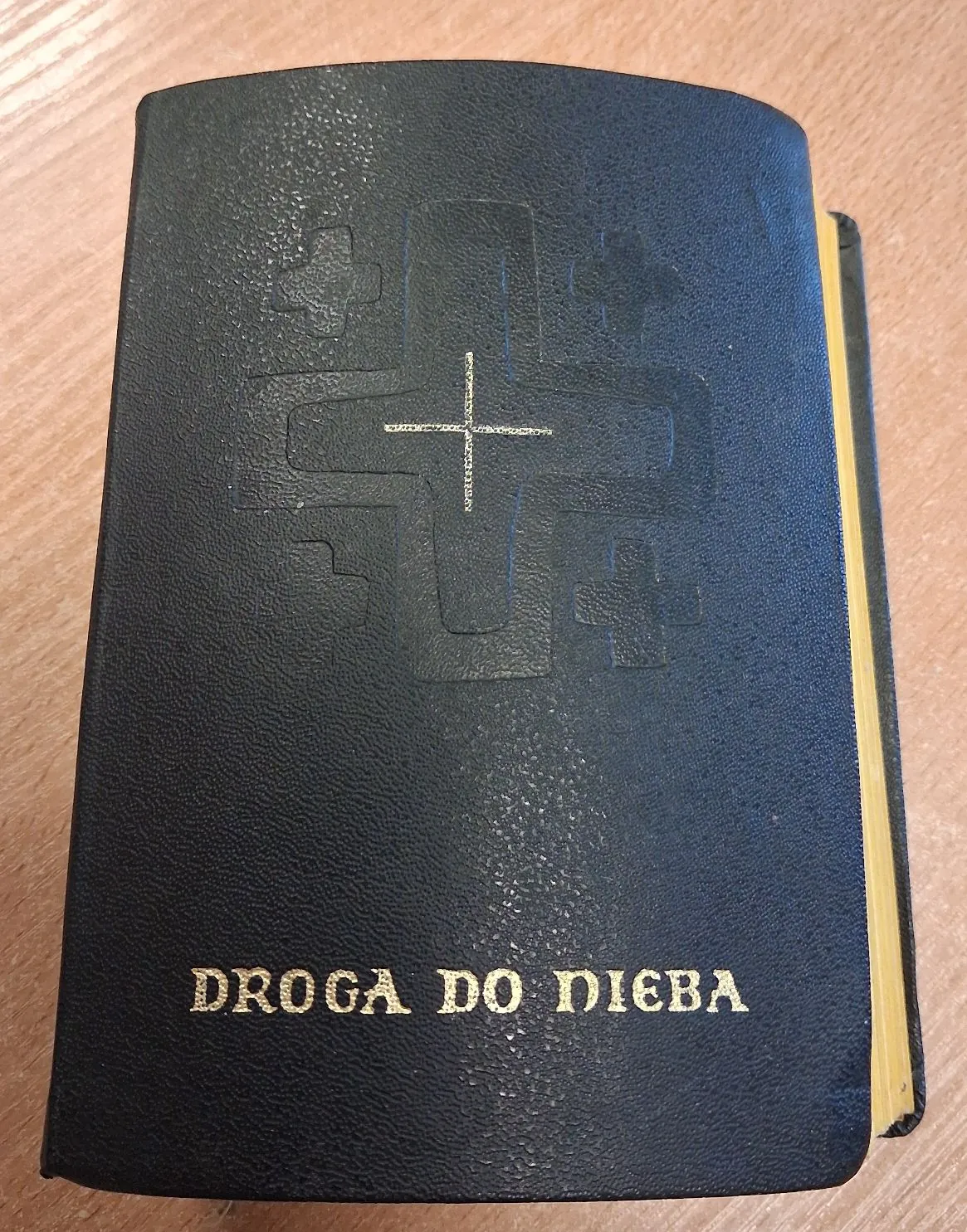 Czarna, twarda oprawa książki z tłoczonym motywem krzyża i mniejszymi krzyżykami wokół niego. Na dole okładki znajduje się złoty napis: DROGA DO NIEBA