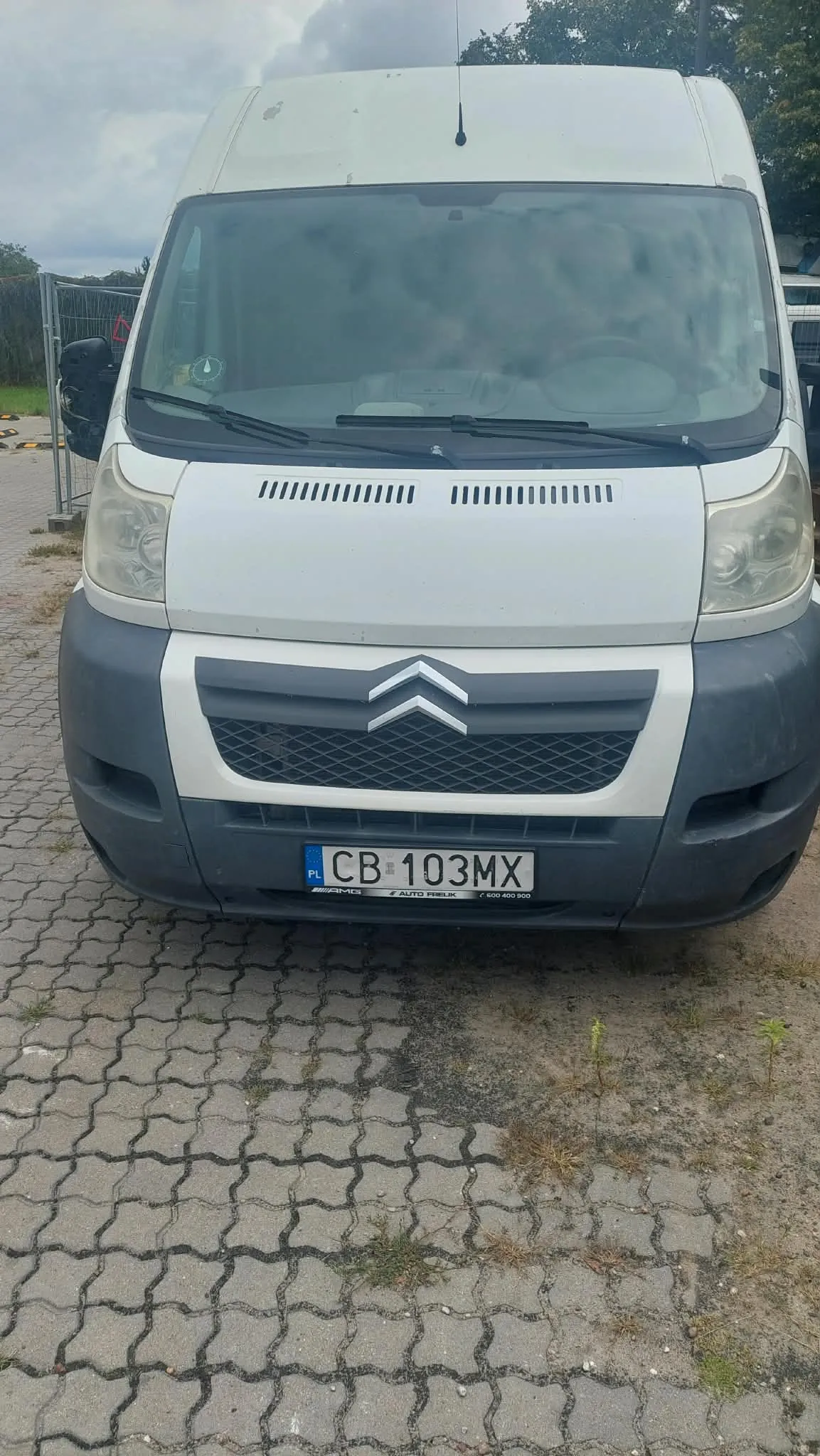 Widok z przodu białego vana marki Citroën z szarym zderzakiem. Pojazd posiada polską tablicę rejestracyjną o numerze CB 103MX. Samochód stoi na kostce brukowej.