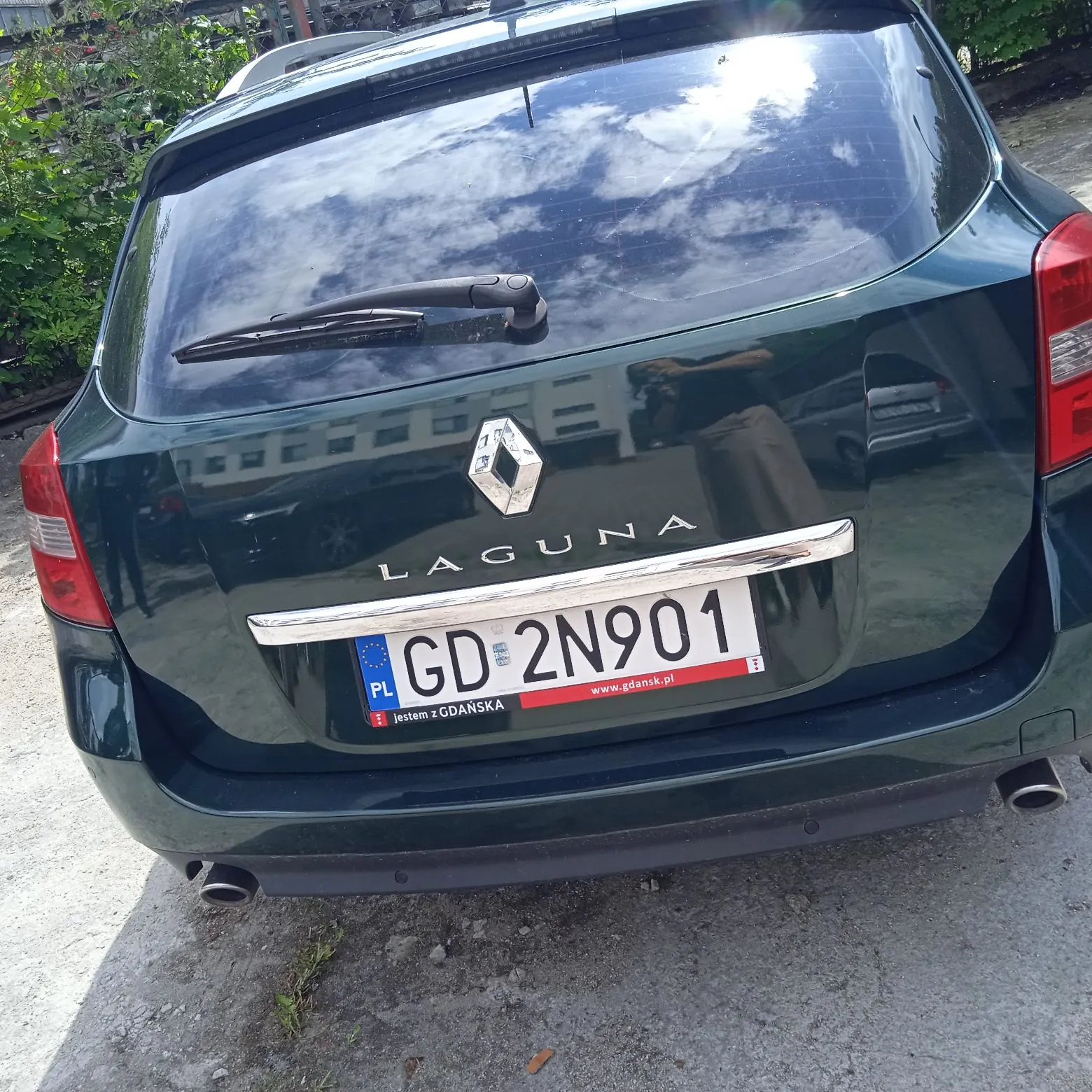 Tylny widok ciemnozielonego samochodu marki Renault Laguna. Na klapie bagażnika znajduje się logo Renault, napis 'LAGUNA' oraz polska tablica rejestracyjna o numerze GD 2N901. Na ramce tablicy widnieje napis 'jestem z GDAŃSKA' oraz adres strony 'www.gdansk.pl'.
