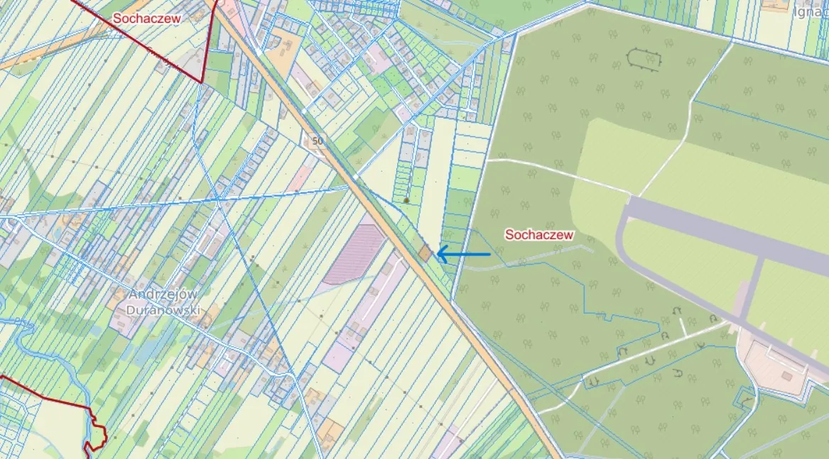Fragment mapy geodezyjnej z zaznaczonymi działkami w kolorach zielonym, żółtym i niebieskim. Na mapie widoczne są napisy 'Sochaczew' oraz 'Andrzejów Durałowski'. Niebieska strzałka wskazuje na konkretną działkę w centralnej części obrazu.